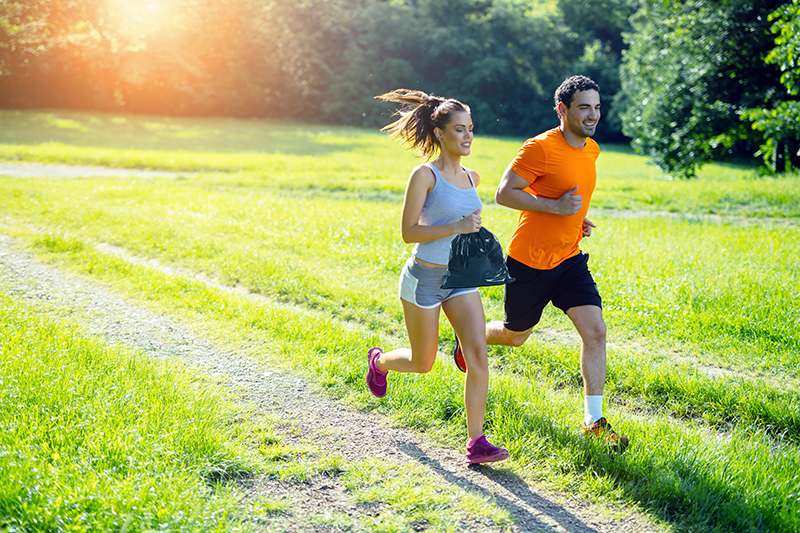 Athletic couple jogging in nature in good spirit