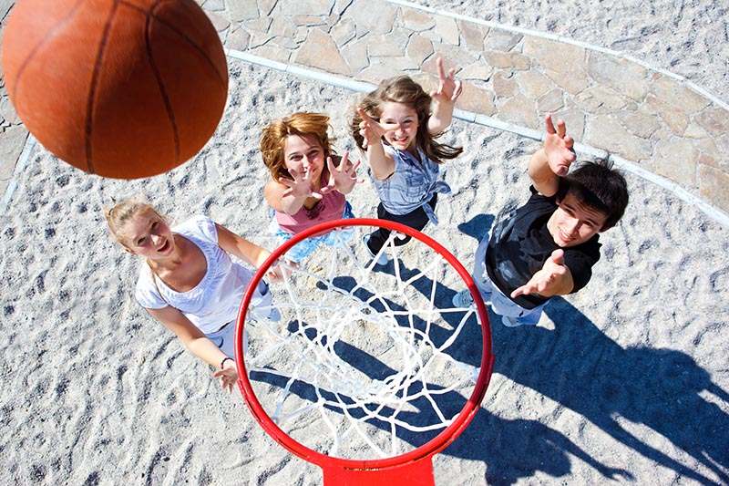 Teenagers team playing street basketball