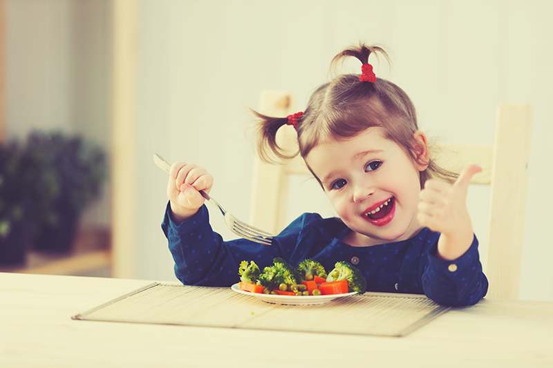 Kind beim Gemüse Essen, gücklich