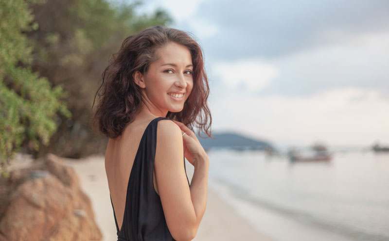 Frau mit rückenfreiem Kleid am Strand