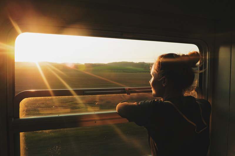 Eine Frau die beim Zugfahren aus dem Fenster schaut
